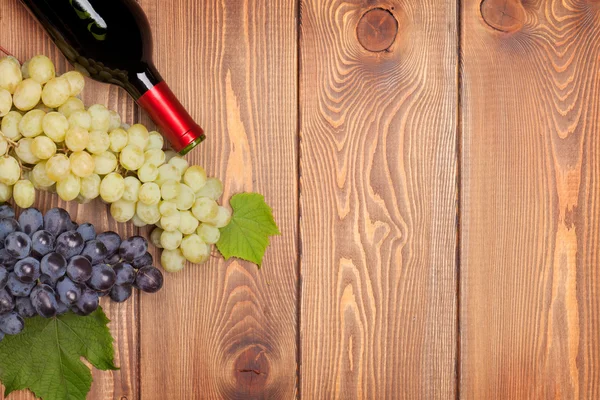 Red wine bottle and bunch of grapes — Stock Photo, Image