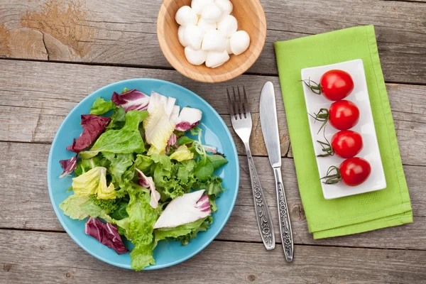 Fresh healthy salad, tomatoes, mozzarella on wooden table — Stock Photo, Image