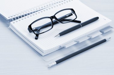 Gözlük, boş not defteri ve kalem ile ofis masaları