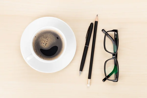 Escritório com xícara de café, suprimentos e óculos — Fotografia de Stock