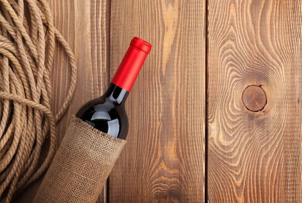 Červené víno láhev rustikální dřevěný stůl pozadí. — Stock fotografie