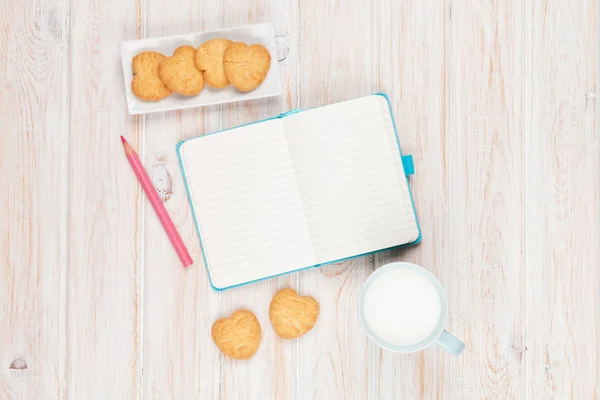 Tasse Milch, herzförmige Kekse und Notizblock — Stockfoto