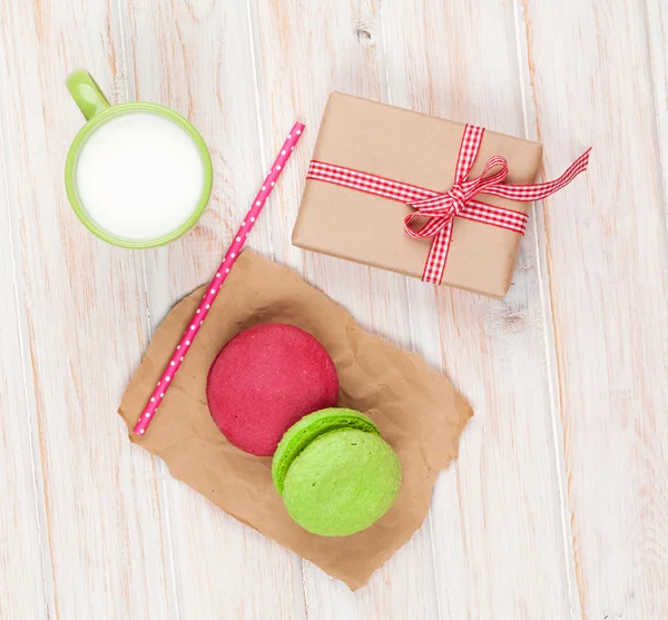 Kleurrijke macarons, kopje melk en geschenk doos — Stockfoto