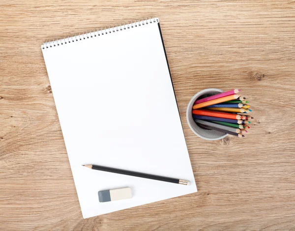 Prázdný papír a barevné tužky na dřevěný stůl — Stock fotografie