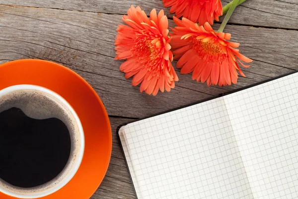 Bloc de notas en blanco, taza de café y flores de gerberas naranjas — Foto de Stock