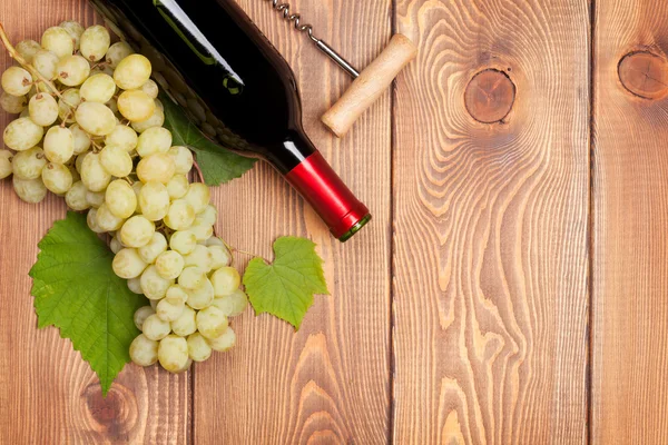 Red wine bottle and bunch of white grapes — Stock Photo, Image