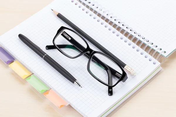 Office tabel met bril op Kladblok — Stockfoto