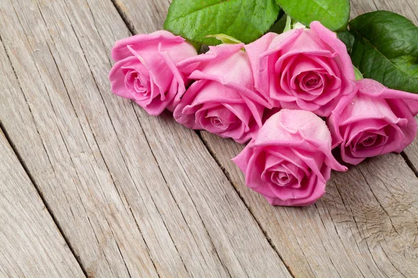 Ramo de rosas rosadas sobre mesa de madera —  Fotos de Stock