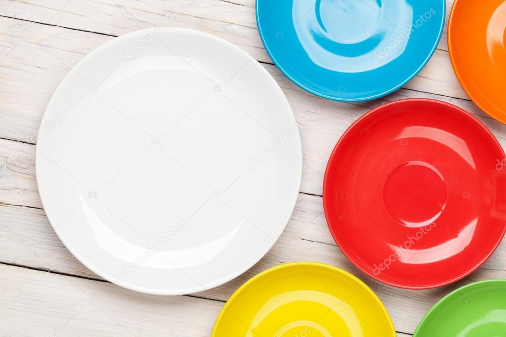 Colorful plates over  wooden table