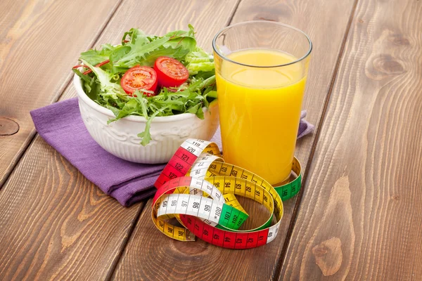 Salade, oranje glas en meetlint — Stockfoto