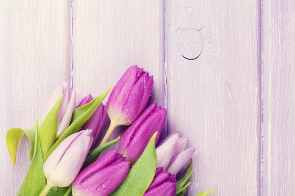 Фиолетовые тюльпаны на деревянном столе — стоковое фото