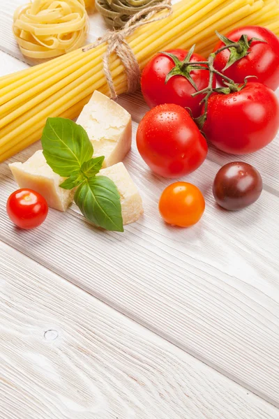 Pasta, tomater, basilika på träbord — Stockfoto