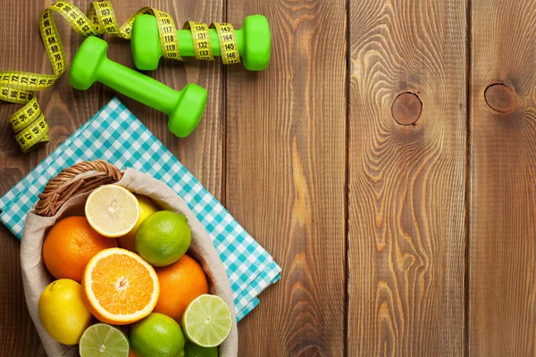 Citrusvruchten in mand en dumbells. — Stockfoto