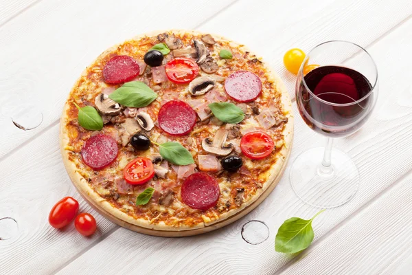 Pizza italiana y vino tinto sobre mesa de madera —  Fotos de Stock