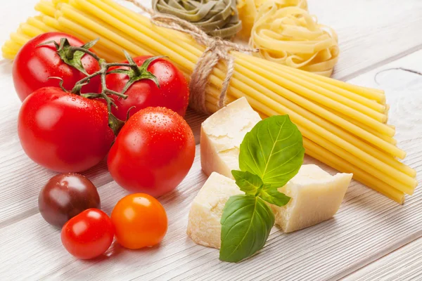 Pasta, tomatoes, basil on wooden table — Stock Photo, Image