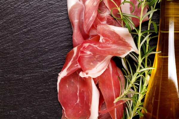 Prosciutto with rosemary and olive oil — Stock Photo, Image
