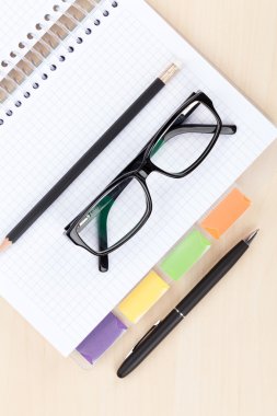 table with glasses, blank notepad and pencil