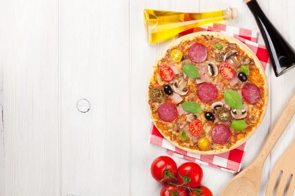 Pizza con pepperoni, tomates, aceitunas y albahaca —  Fotos de Stock