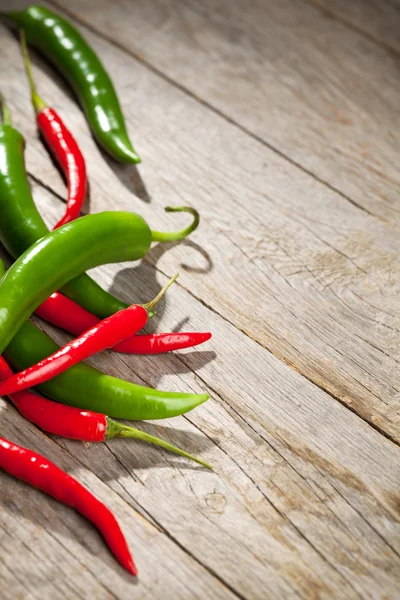 Barevné chili peppers na dřevěný stůl — Stock fotografie