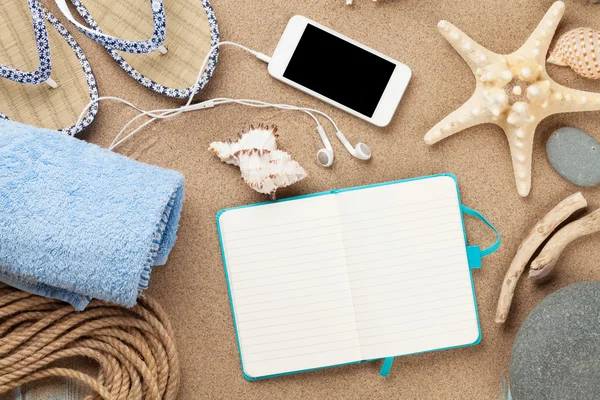 Smartphone en Kladblok op zee zand — Stockfoto