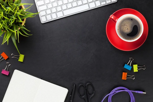 table with computer, supplies, coffee and flower