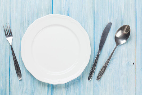 Empty plate and silverware over wooden table