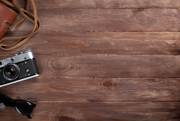 Camera and sunglasses on wooden desk