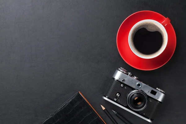 Desk with camera, supplies and coffee cup — Stock Photo, Image