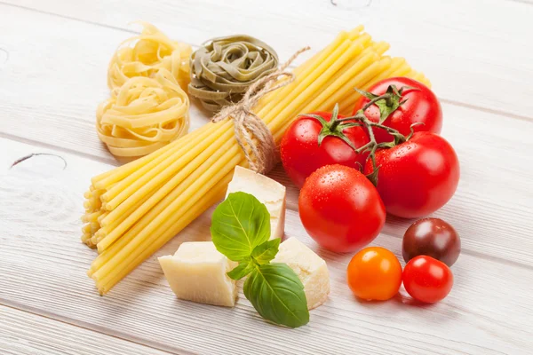 Pasta, tomater, basilika på träbord — Stockfoto