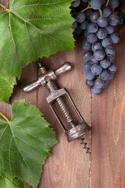Red grapes and vintage corkscrew — Stock Photo, Image