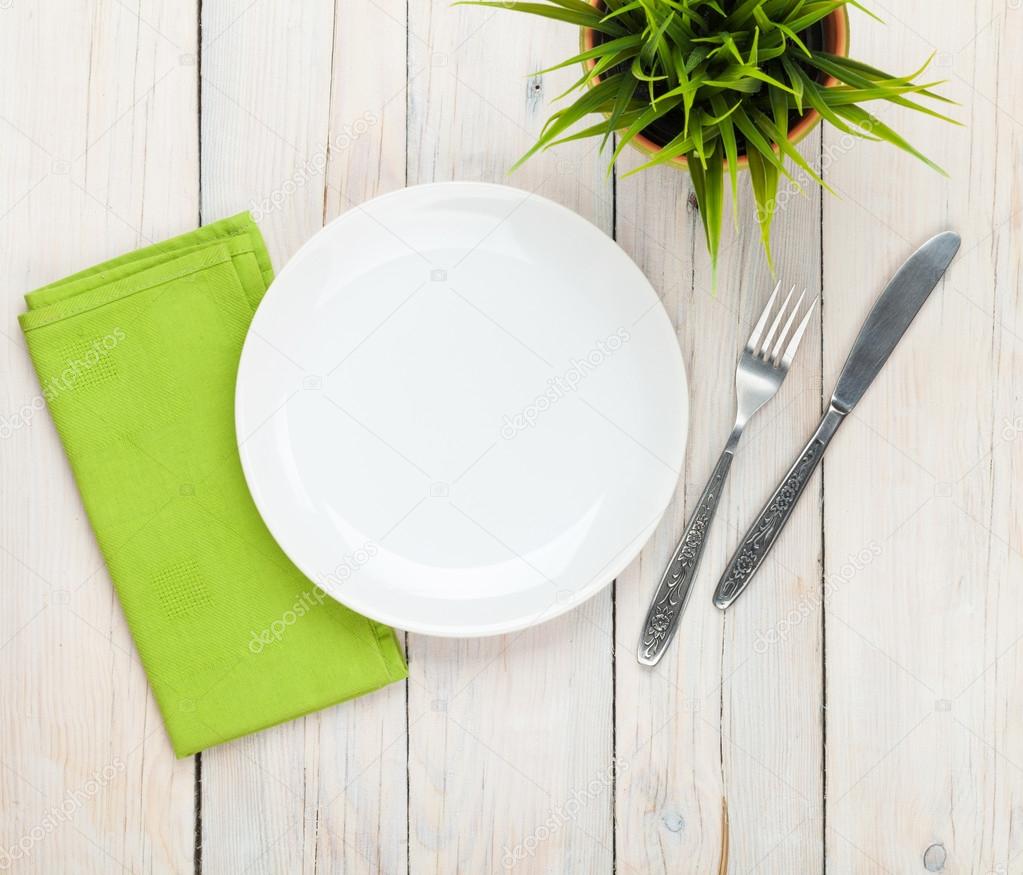 Empty plate and silverware over wooden table