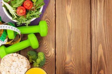 Dumbells, mezura ve ahşap masa üzerinde sağlıklı gıda