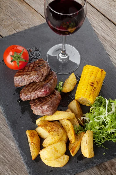Bistecca con patate alla griglia, mais, insalata e vino rosso — Foto Stock