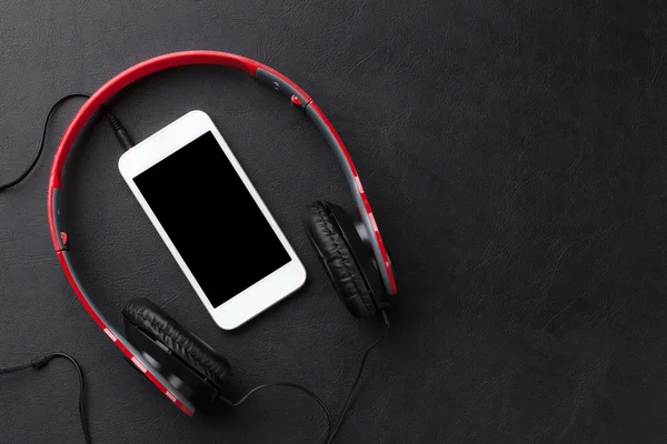 Casques et smartphone sur le bureau — Photo