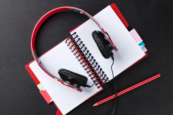 Headphones over notepad on desk — Stock Photo, Image