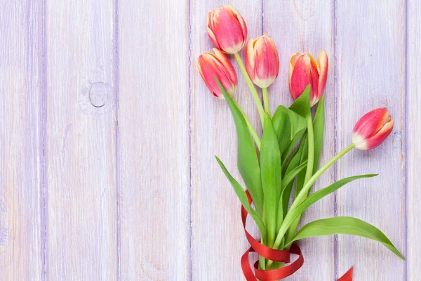 Czerwone tulipany na fioletowy drewniany stół — Zdjęcie stockowe
