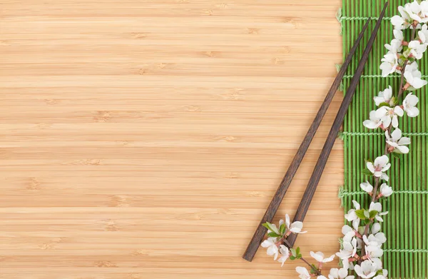 Chopsticks e ramo sakura sobre esteira de bambu — Fotografia de Stock