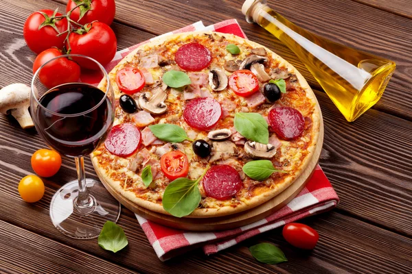 Pizza italiana con salame piccante, pomodori, olive, basilico e wi rosso — Foto Stock