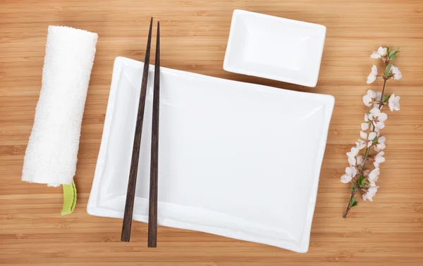 Prázdné talíře, jídelní hůlky a sakura větev — Stock fotografie