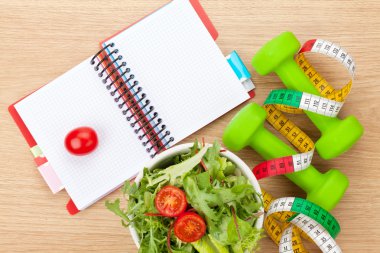 Dumbells, mezura, gıda ve not defteri