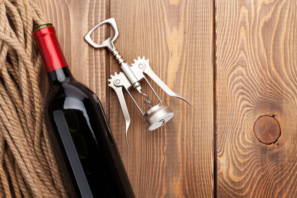 Red wine bottle and corkscrew on table