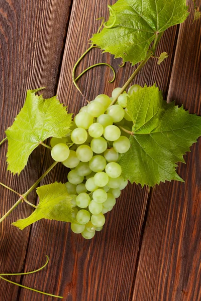 Ramo de uvas blancas con hojas sobre madera —  Fotos de Stock