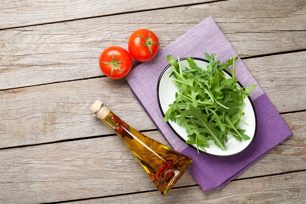 Салат из рукколы, помидоры и бутылка оливкового масла — стоковое фото
