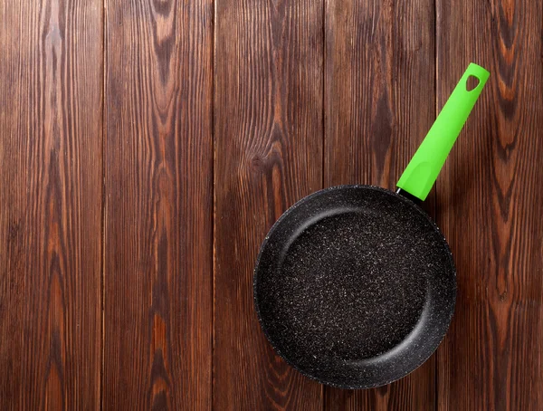Frying pan on wooden table — Stock Photo, Image