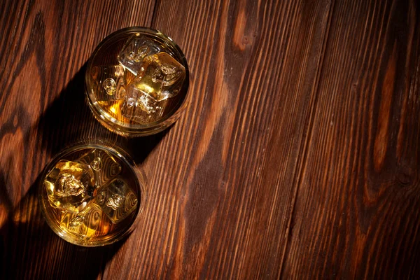 Glasses of whiskey with ice on wood — Stock Photo, Image