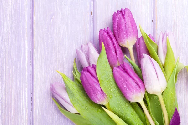 Purple tulips over wooden table — Stock Photo, Image