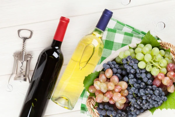 Бутылки и виноград белого и красного вина — стоковое фото