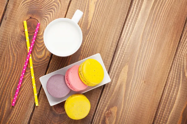 Colorful macaroons cookies and cup of milk — Stock Photo, Image