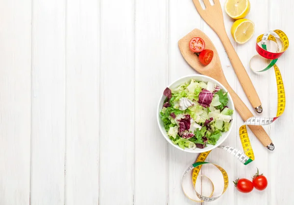 Fresh healthy salad, utensils and tape measure — Stock Photo, Image