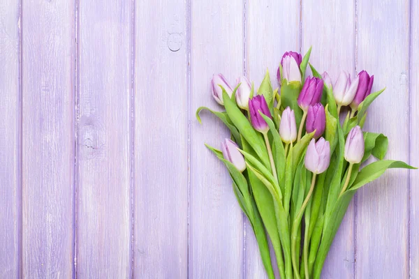 Purple tulips over wooden table — Stock Photo, Image